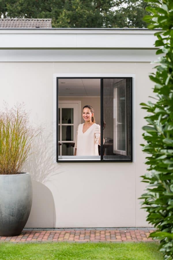 Unilux plissé raamhor voor een geopend raam, gezien vanuit de tuin