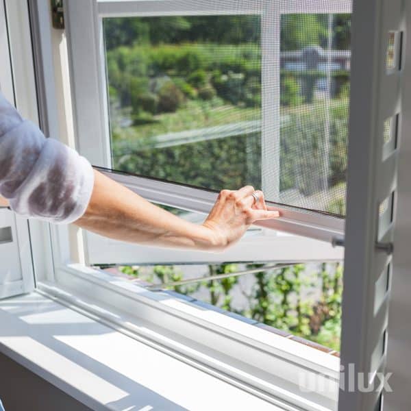 Een Unilux raamrolhor wordt met de hand omlaag geschoven voor een open raam